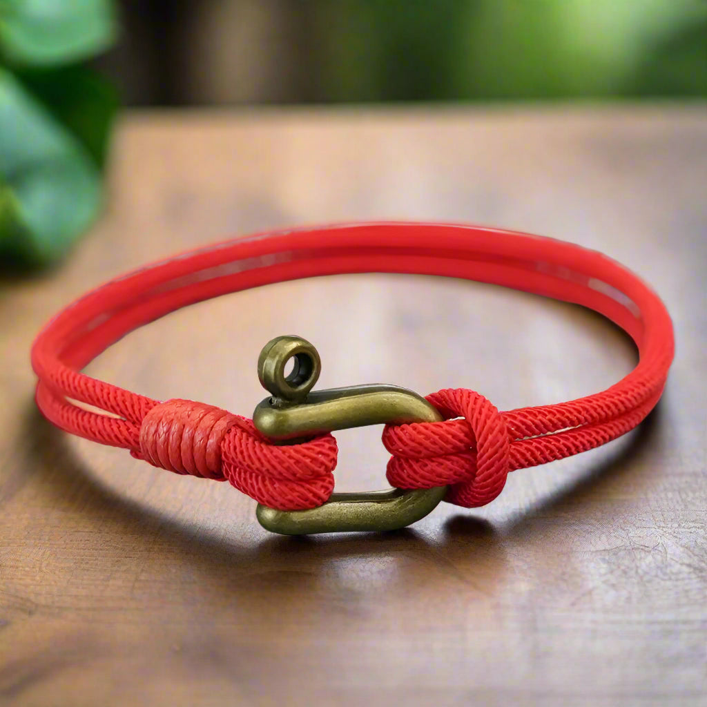 Red bracelet with a brass clasp on a textured surface