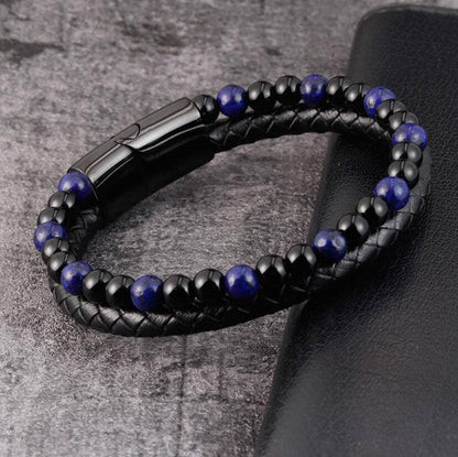 Black braided leather and blue beaded bracelet on a textured surface