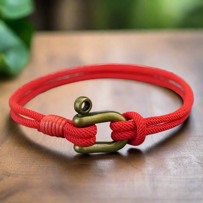 Red bracelet with a brass clasp on a textured surface