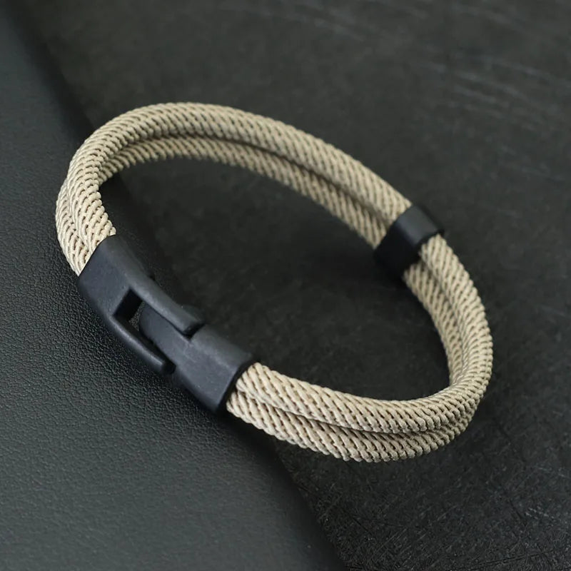 Beige braided bracelet with a black clasp on a dark textured surface
