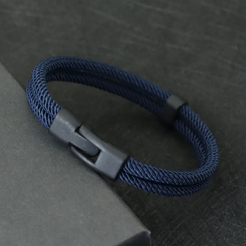 Navy braided bracelet with a gray clasp on a dark textured surface