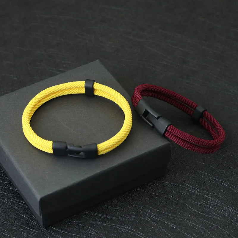 Yellow and red braided bracelets on a black box with a dark textured background