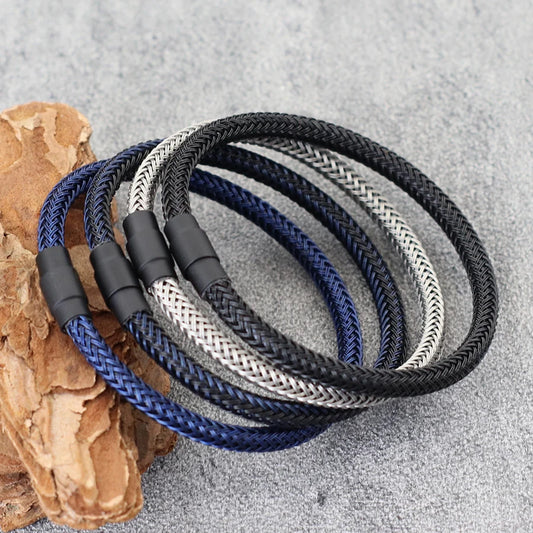 Three braided ropes in black, blue, and gray on a textured surface.