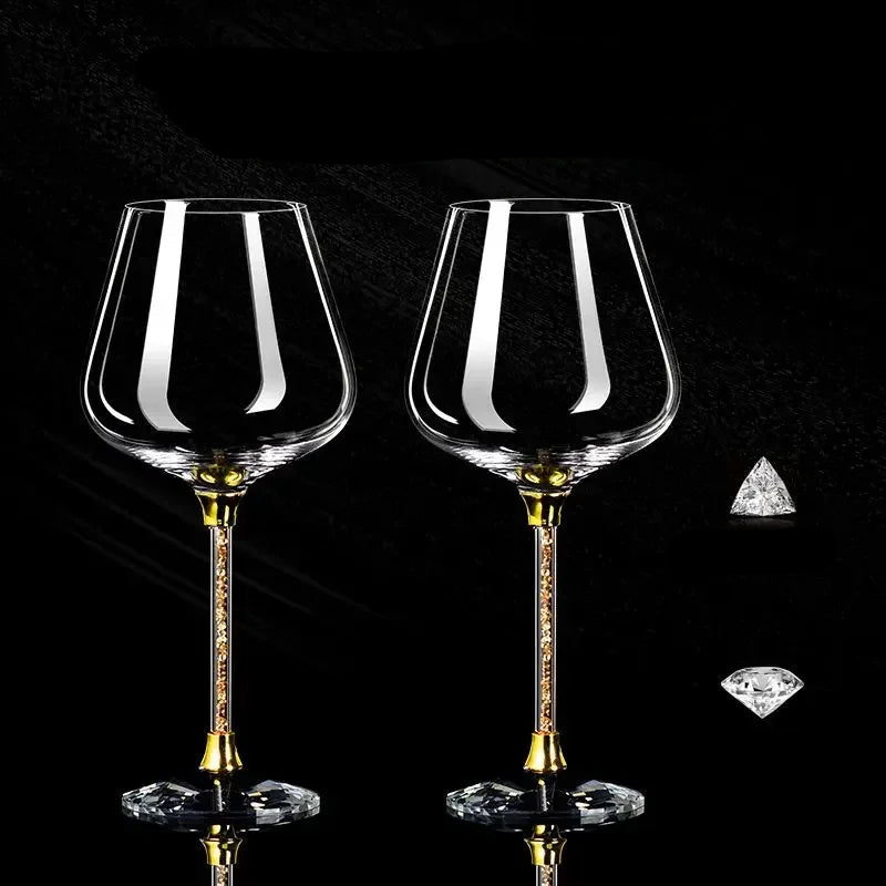 Two crystal wine glasses with gold stems on a black background