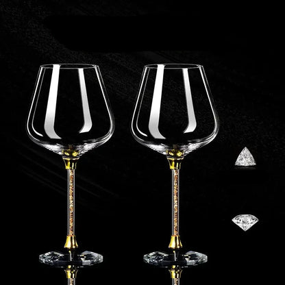 Two crystal wine glasses with gold stems on a black background