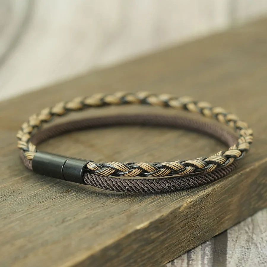 Braided leather bracelet with metal clasp on a wooden surface