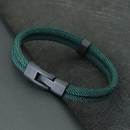 Green braided bracelet with a black clasp on a dark gray background