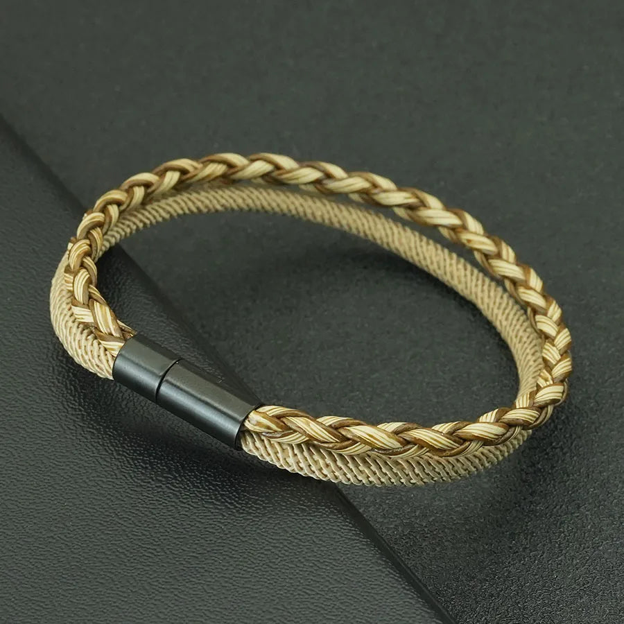 Gold braided bracelet with a black clasp on a dark background