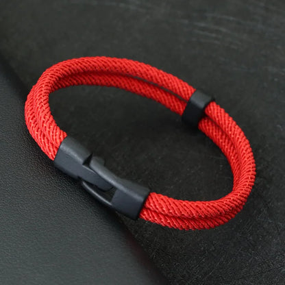 Red braided bracelet with a black clasp on a dark textured background