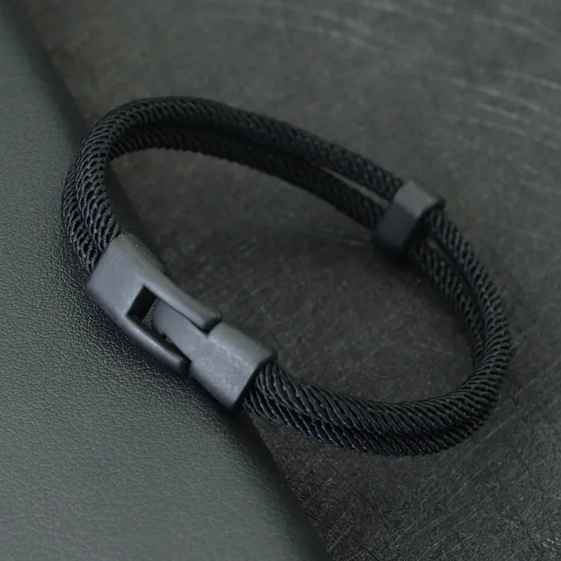 Black braided bracelet on a dark textured surface