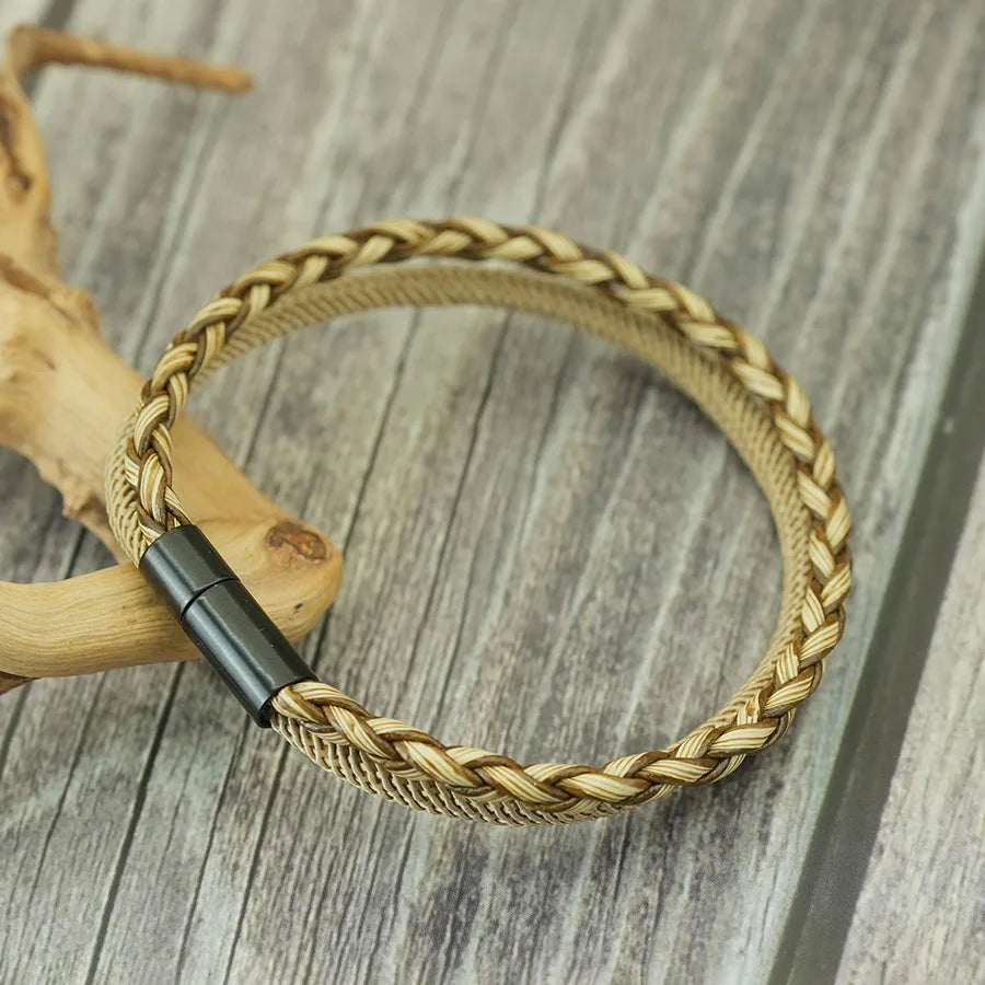 Braided gold bracelet with black clasp on a wooden surface