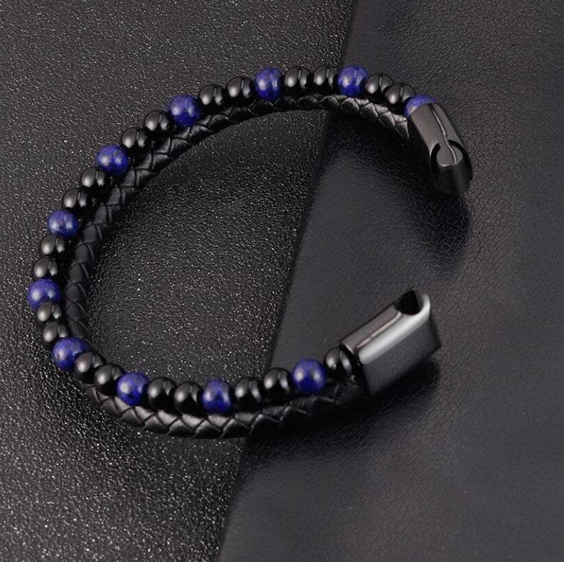Black beaded bracelet with blue beads on a dark textured surface